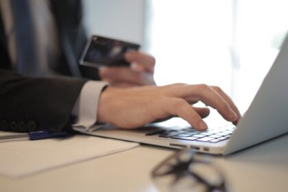 Man in suit using laptop and credit card for online transaction at work.